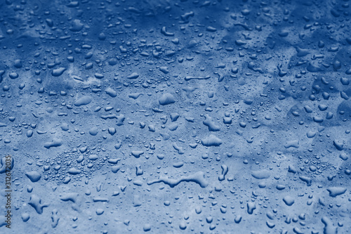 blue water drops texture on the glass background. Classic blue toning trend 2020