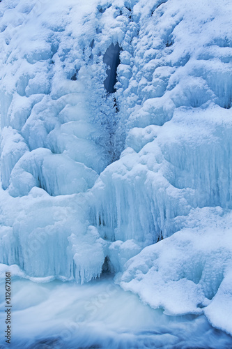 Winter landscape of the Comstock Creek cascade framed by ice and captured with motion blur, Michigan, USA 