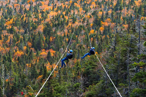 two people sliding down very long and fast zipline during autumn in Stowe, Vermont