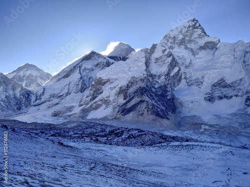 Everest mountain in Himalayas just before sunrise. Colorful snow is blown away from the top. View from the slope of Kala Patthar mountain. Theme of travel in Nepal. Clear blue sky.