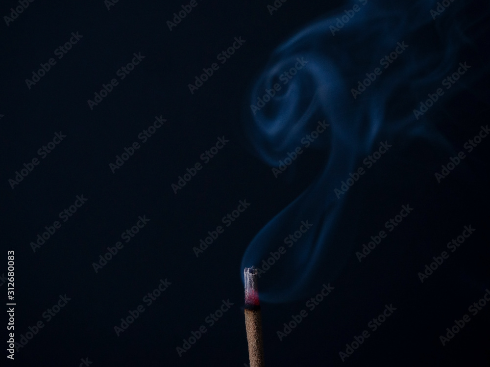 Burning aromatic incense stick in a meditation room with beautiful gray smoke on a black background with copy space. Used for aesthetic reasons, aromatherapy, meditation, and ceremony. Burning aromatic incense stick in a meditation room with beautiful gray smoke on a black background with copy space. Used for aesthetic reasons, aromatherapy, meditation, and ceremony.