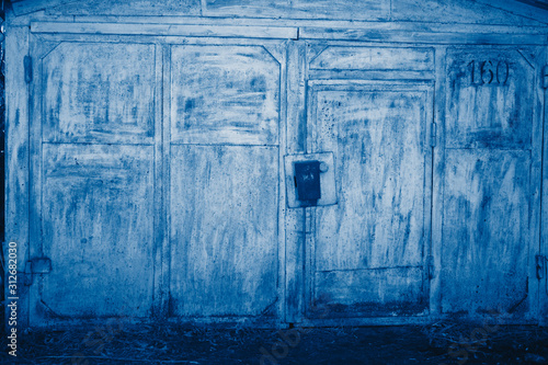 Colored peeling garage door and wall. Texture and background. toned  in classic blue trendy color of the year 2020 © sotnikova_vera