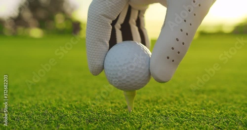 Golfer placing golf ball on the tee at golf course. Closeup.