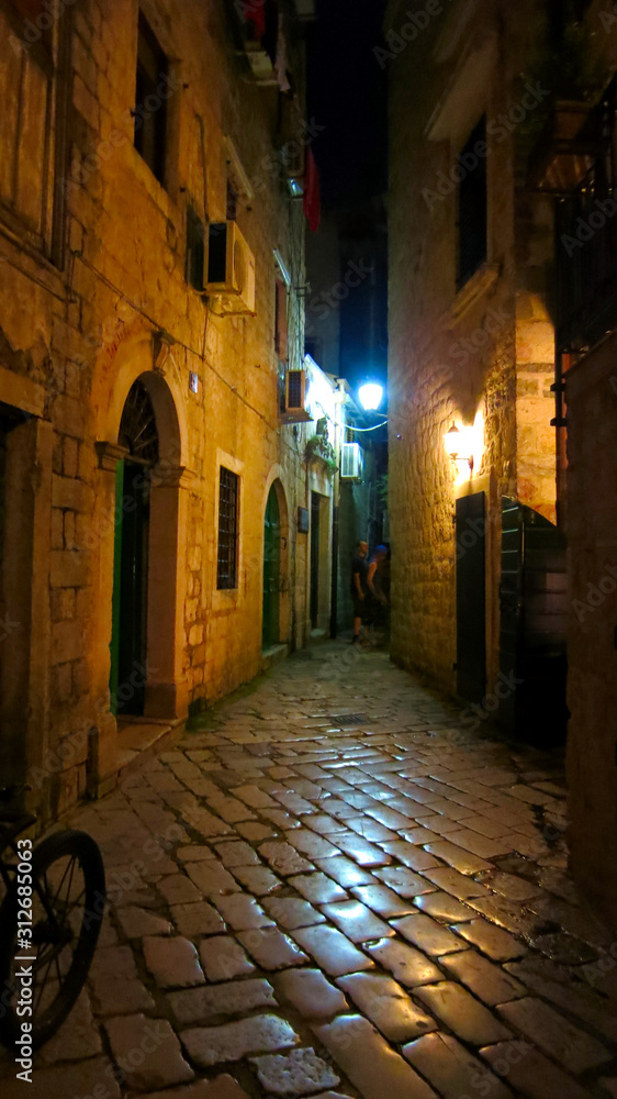Medieval vintage narrow street with ancient stone pavers in old european city Kotor in Montenegro at night