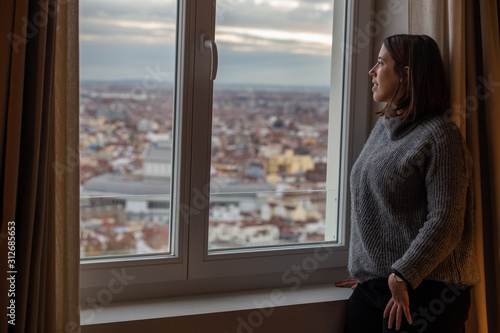 rear view of young woman sitting on a window from her room and looking outside on a sunny day with Madrid skyline views Free Download rear view of young woman sitting on a window from her room and looking outside on a sunny day with Madrid skyline views - GFXLoad