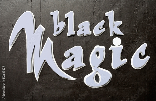 BLACK MAGIC sign mounted on black building wall. photo