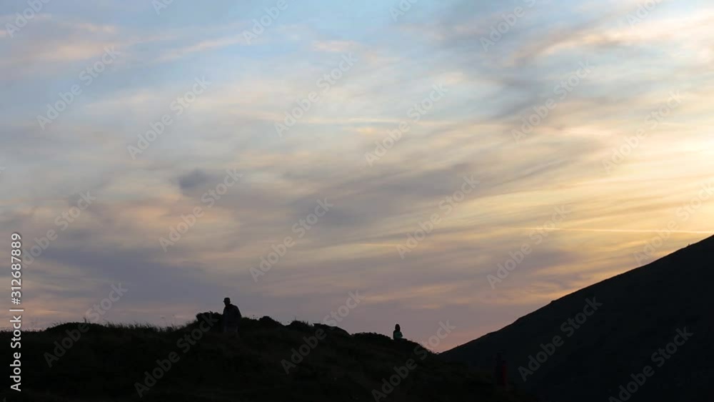 Dark silhouettes of hikers trekking on evening mountain terrain. Dark silhouettes of hikers trekking on evening mountain terrain.