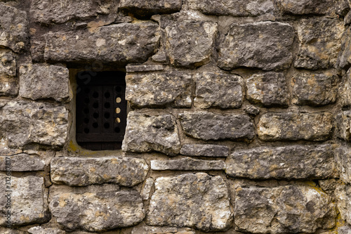 Ancient stone wall with small wooden window