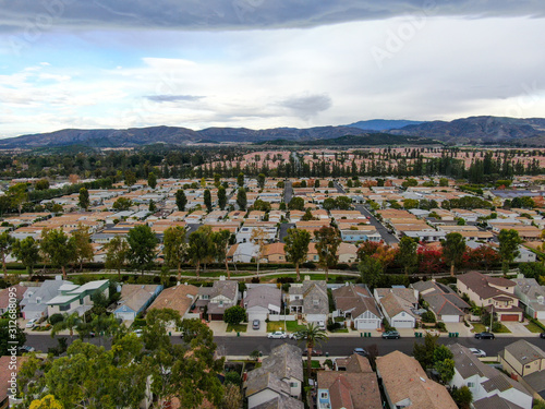 Aerial view of urban sprawl. Suburban packed homes neighborhood with road.during clouded day. Vast subdivision in Irvine, California, USA