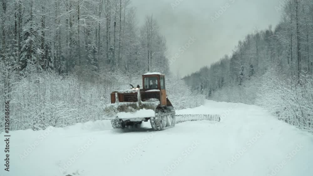 an old tractor clears a forest road in winter an old tractor clears a forest road in winter