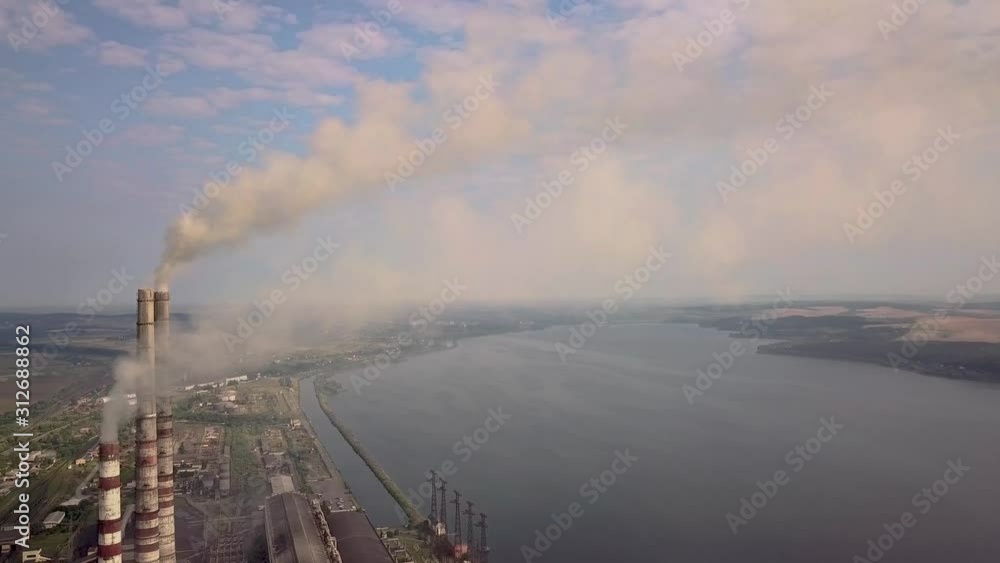 Aerial view of high chimney pipes with grey smoke from coal power plant. Production of electricity with fossil fuel. Aerial view of high chimney pipes with grey smoke from coal power plant. Production of electricity with fossil fuel.