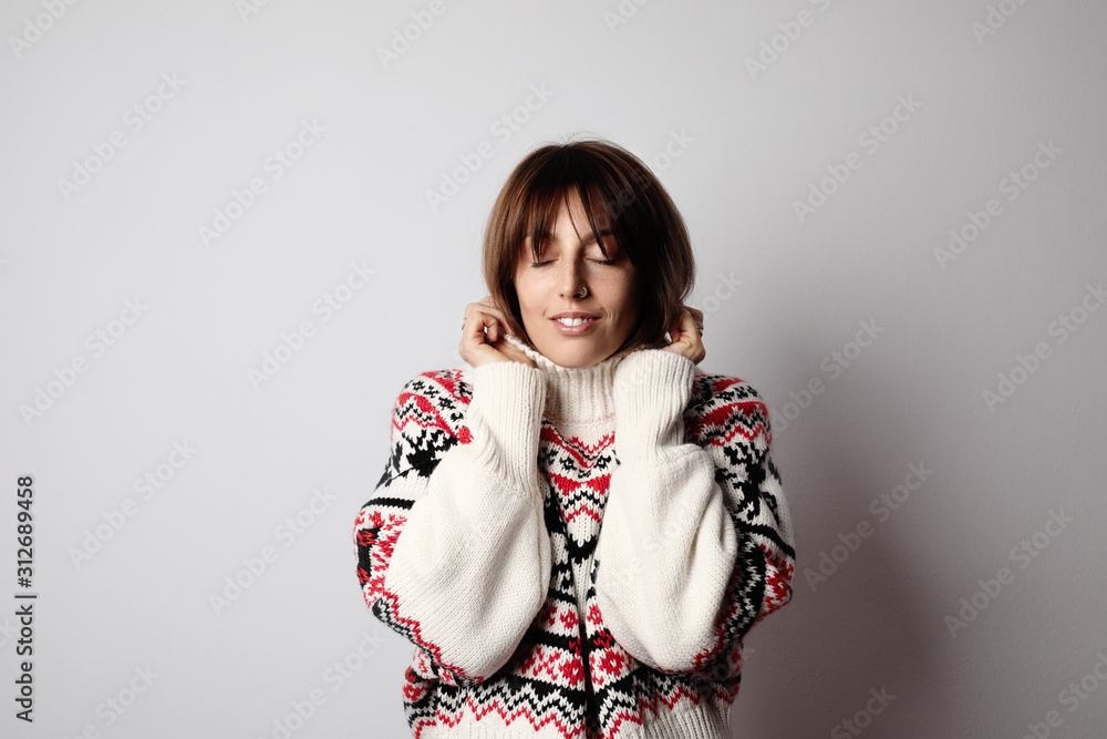 Young woman wearing warm sweater and posing on white wall. Isolated. Young woman wearing warm sweater and posing on white wall. Isolated.