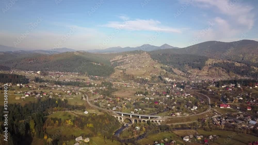Aerial view of autumn mountain landscape with evergreen pine trees and yellow fall forest with magestic mountains in distance. Town of Vorokhta in Carpathian mountains, Ukraine. Aerial view of autumn mountain landscape with evergreen pine trees and yellow fall forest with magestic mountains in distance. Town of Vorokhta in Carpathian mountains, Ukraine.