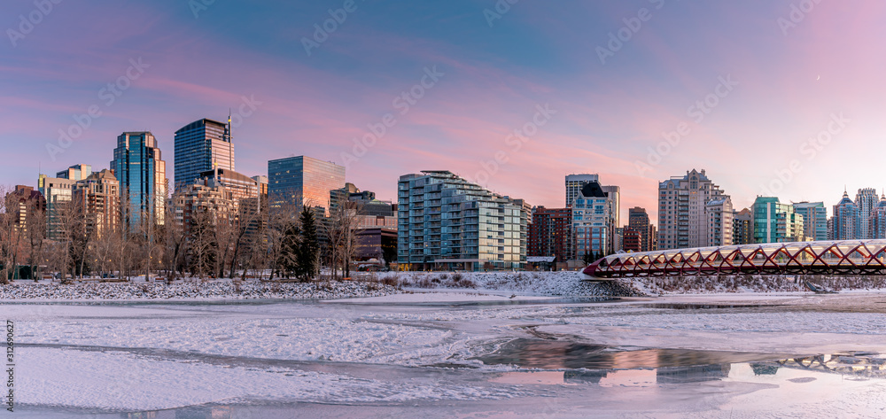 Fototapeta premium Evening skyline view along the Bow River in Calgary, Alberta. Peace Bridge visible. 