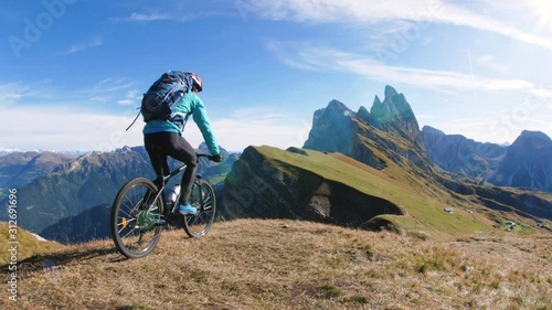 Young man with mountain bike cycling on Seceda mountain peak at sunrise. Puez Odle, Trentino, Dolomites, Italy.