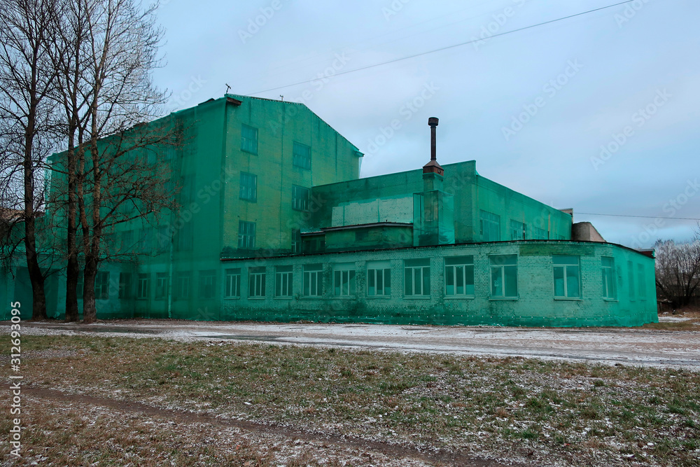 building of an old abandoned factory, covered with a green mesh for repair
