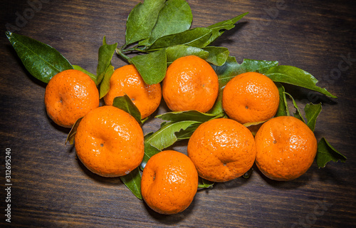 Tangerines with leaves on a black wooden table