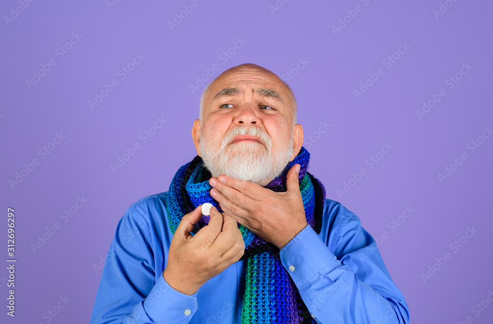 Sore throat. Treatment pill. Medicine. Senior man taking pharmaceutical pills. Bearded man with sore throat taking pills. Ill man take pill for throat. Man wrapped in scarf suffering from sore throat. Sore throat. Treatment pill. Medicine. Senior man taking pharmaceutical pills. Bearded man with sore throat taking pills. Ill man take pill for throat. Man wrapped in scarf suffering from sore throat.