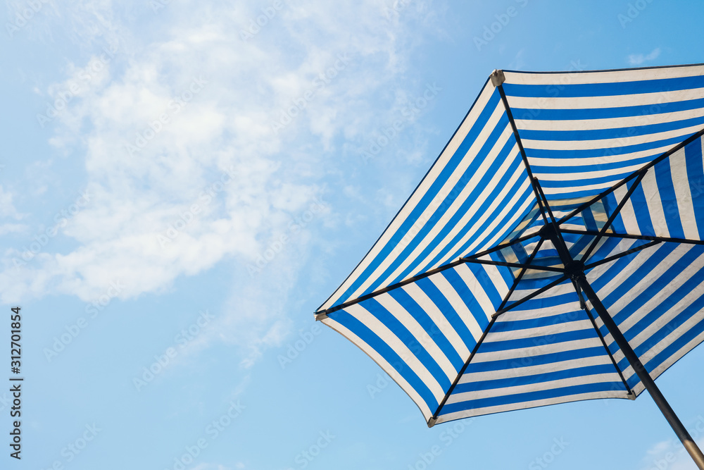 blue striped beach umbrella with sky background