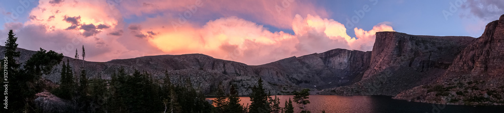 Panorama of pink sunset on mountain lake