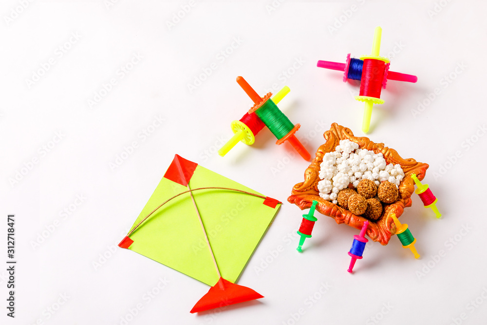 Celebrate Indian festival makar sankranti with colorfull kite,sesame seed ball,tilgul and chakri over white background Celebrate Indian festival makar sankranti with colorfull kite,sesame seed ball,tilgul and chakri over white background