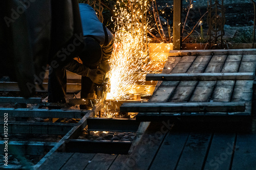 A construction worker using an angle grinder producing a lot of sparks