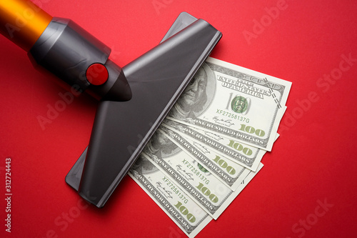 vacuum cleaner nozzle sucking money dollar bill on red background