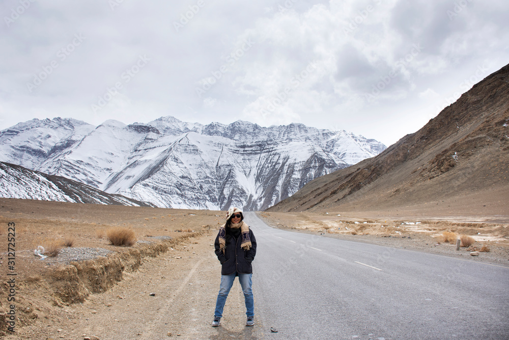 Travelers thai woman travel visit and posing for take photo with landscape high range mountain on Srinagar Leh Ladakh highway at Leh Ladakh village in Jammu and Kashmir, India at winter season