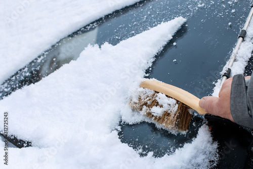 A man is removing snow from the car.