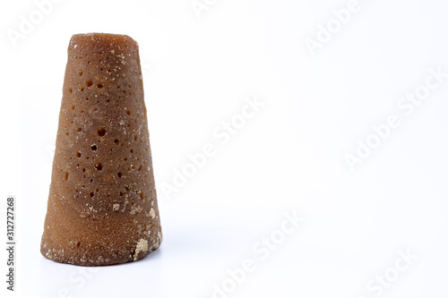 Piloncillo cone of unrefined raw brown cane sugar isolated on white background with space or room for text