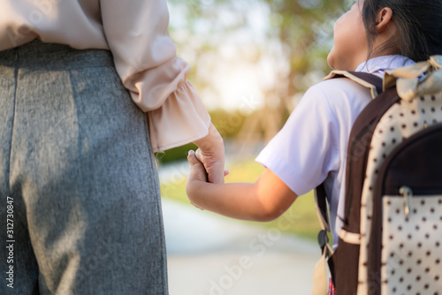 Close up of Happy Asian mother and daughter preschool student walking to school. Beginning of lessons. First day of fall. Parenthood or love and bonding expression concept.