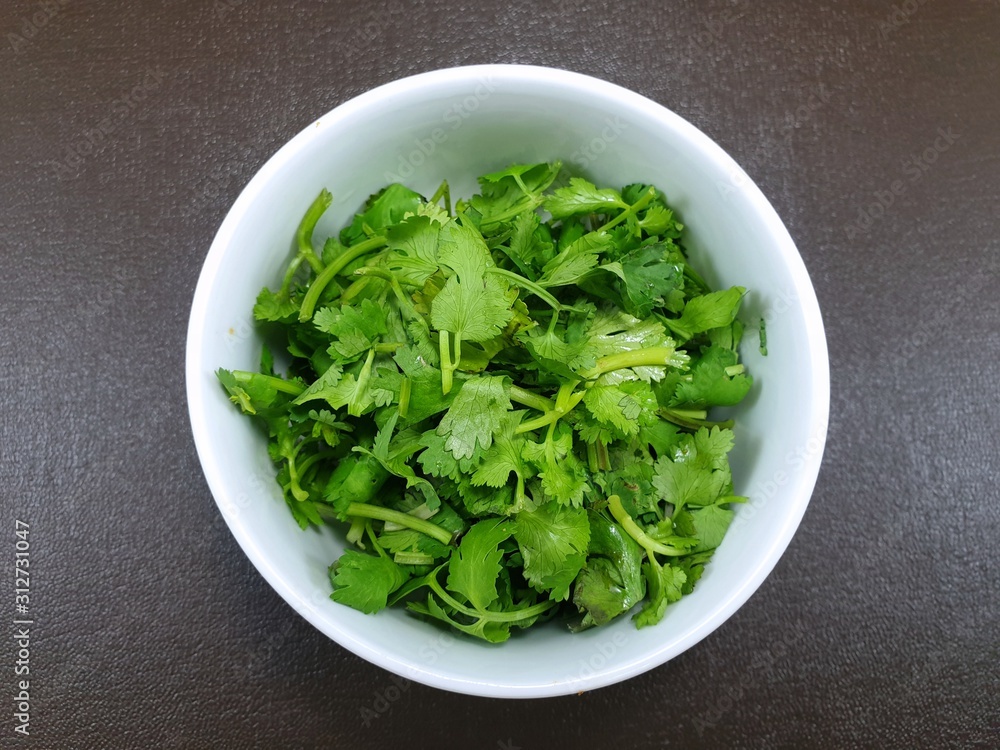 Top view of fresh coriander leaf in white bowl on wooden table as a background, for making cooking, healthy food concept Top view of fresh coriander leaf in white bowl on wooden table as a background, for making cooking, healthy food concept