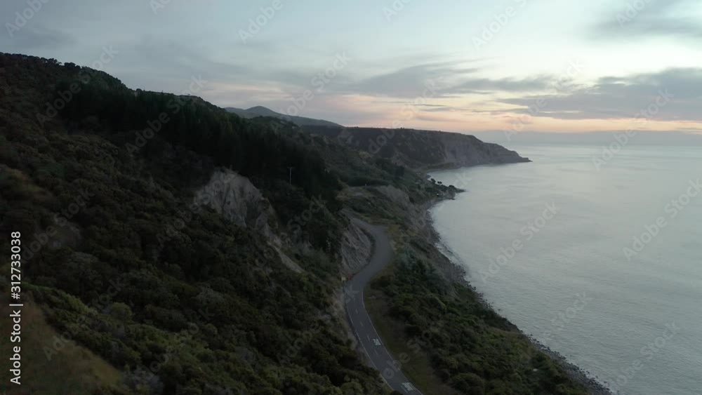 Empty road on the edge of a rocky coast at sunset in New Zealand - Tracking drone shot Empty road on the edge of a rocky coast at sunset in New Zealand - Tracking drone shot