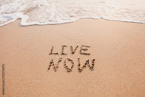 live now, mindfulness concept, text written on the sand