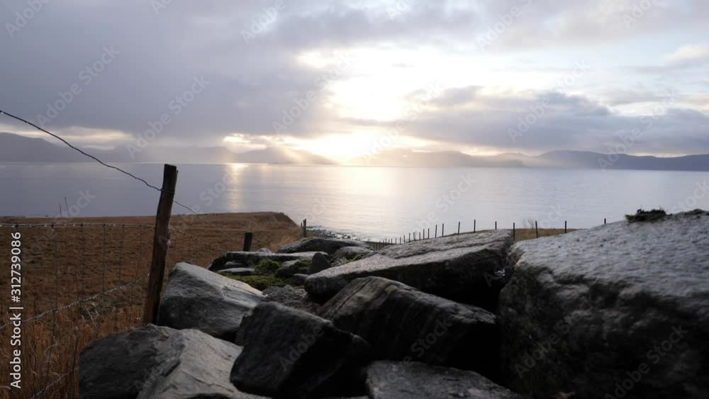 Ancient stone sheep fence leading down to the shoreline of a large lake or ocean at sunset, - low, wide angle pan Ancient stone sheep fence leading down to the shoreline of a large lake or ocean at sunset, - low, wide angle pan