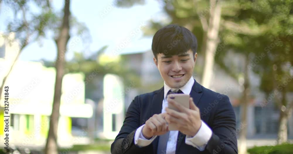 Businessman holding mobile phone while walking on street to office Businessman holding mobile phone while walking on street to office