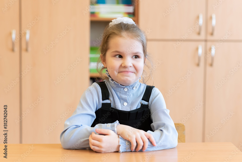 Girl schoolgirl sits at her desk and is surprised. Girl schoolgirl sits at her desk and is surprised.