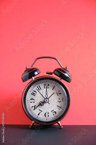 Old, vintage retro alarm clock on a bright red background.