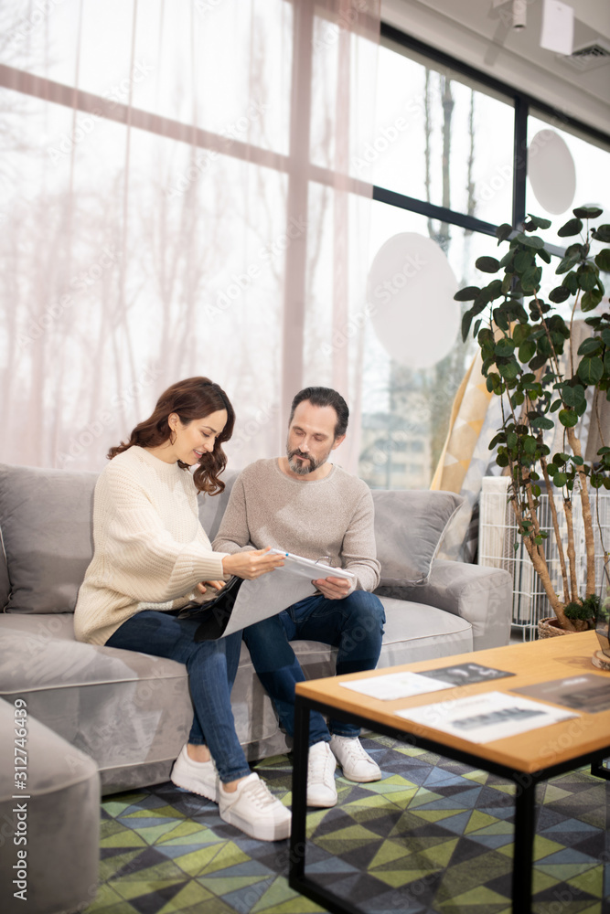Man and woman in furniture salon choosing fabric for sofa Man and woman in furniture salon choosing fabric for sofa
