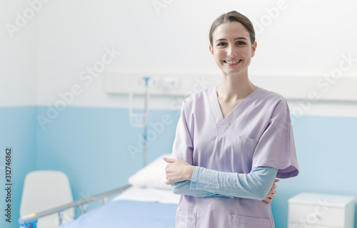 Young nurse posing next to a hospital bed