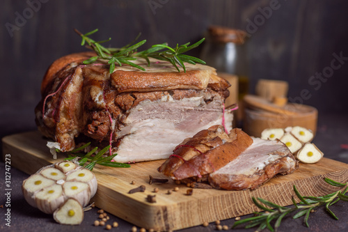 Baked pork brisket with twine on a wooden board. with sliced ​​brisket with rosemary and spices and garlic on a dark background horizontal arrangement