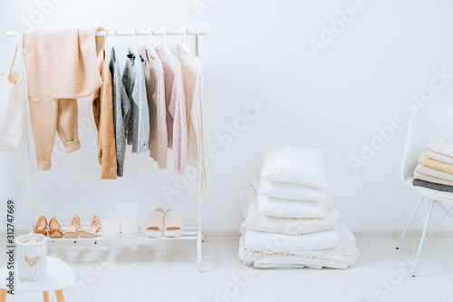 Scandinavian style, bedroom, bed, clothes rack in a modern light style. Female blouses and t-shirts on hanger on white background. Fashion blog, website, social media hero header template