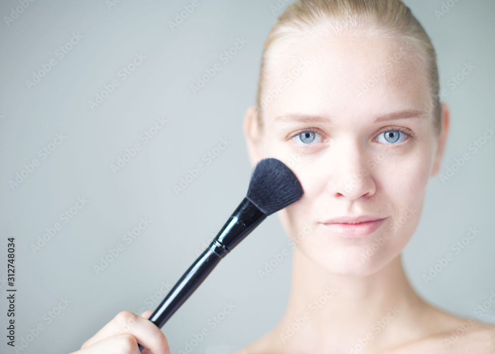 Attractive female applying makeup on her face. Natural beautiful woman with clean skin.Beautiful blonde woman with clean skin applying makeup. . Attractive female applying makeup on her face. Natural beautiful woman with clean skin.Beautiful blonde woman with clean skin applying makeup. .