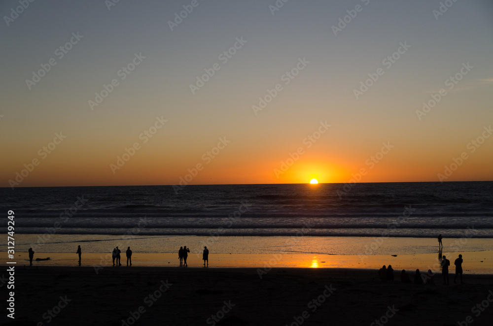 Naklejka premium Beachgoers watch sunset near Crystal Pier in San Diego