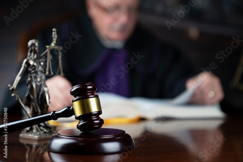 Judge looking through legal code with the wooden gavel in his hand. © zolnierek