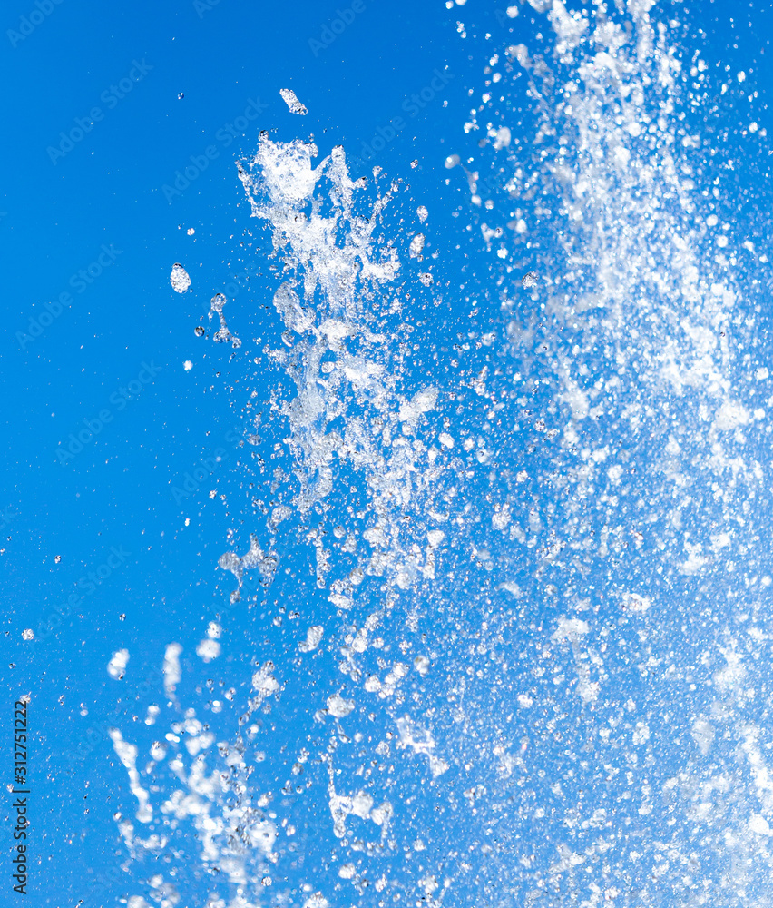 Splashing water from a fountain on a background of blue sky Splashing water from a fountain on a background of blue sky