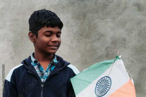 Closeup portrait of the Indian kid holding Tri colored kite in his hands during Makar Sankranti Festival at Wankaner, Gujarat, India photo