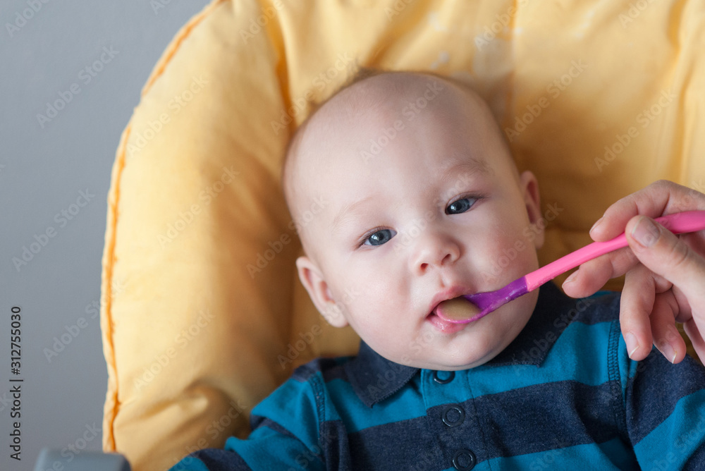 Mom feeds little son baby food from spoon close-up Mom feeds little son baby food from spoon close-up