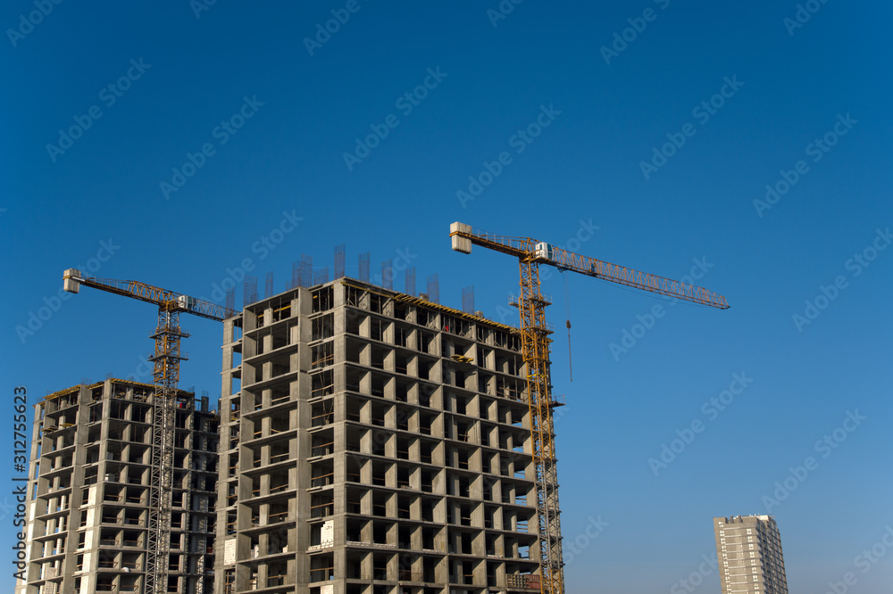 Hydraulic luffing jib tower cranes and workers being poured concrete into foundation. Cement pouring into formwork of building at construction site. Tower cranes constructing a new residential build Hydraulic luffing jib tower cranes and workers being poured concrete into foundation. Cement pouring into formwork of building at construction site. Tower cranes constructing a new residential build
