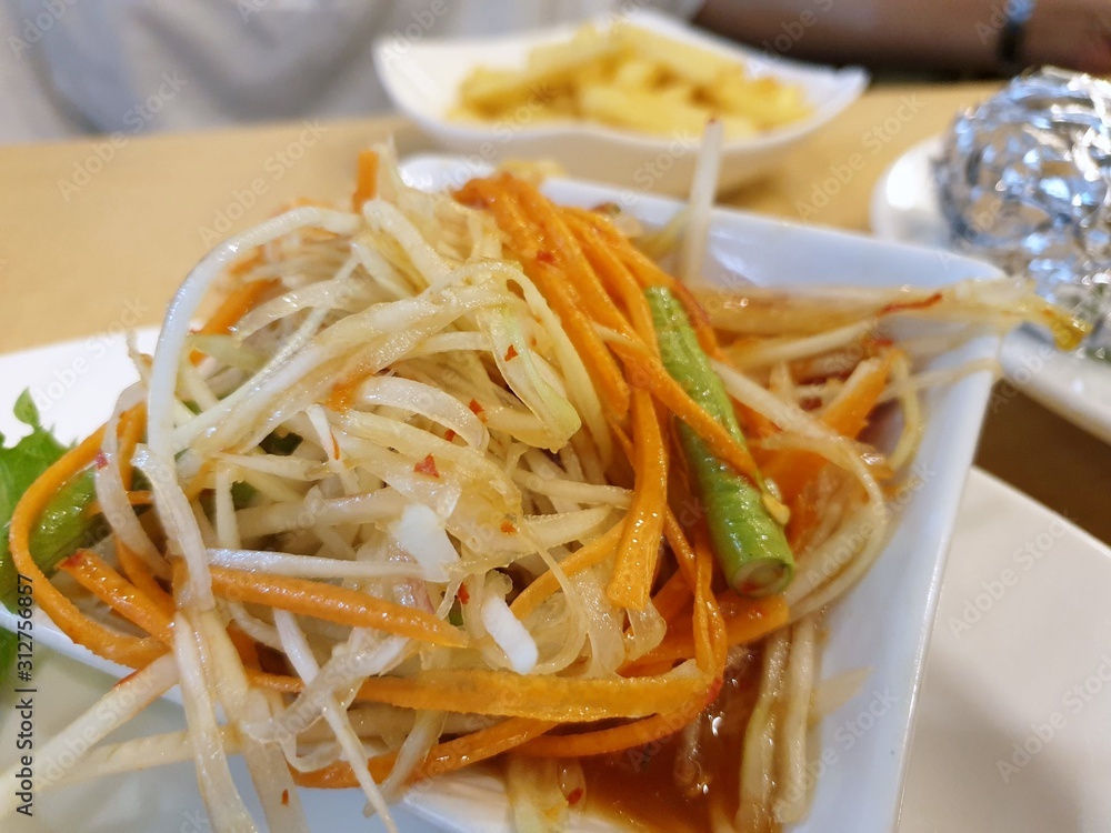 Thai food style, Selective focus of papaya salad with tomato, shrimp, chili and bean on white plate as a background, This food is most popular, Som Tum is Thai traditional Thai food style, Selective focus of papaya salad with tomato, shrimp, chili and bean on white plate as a background, This food is most popular, Som Tum is Thai traditional